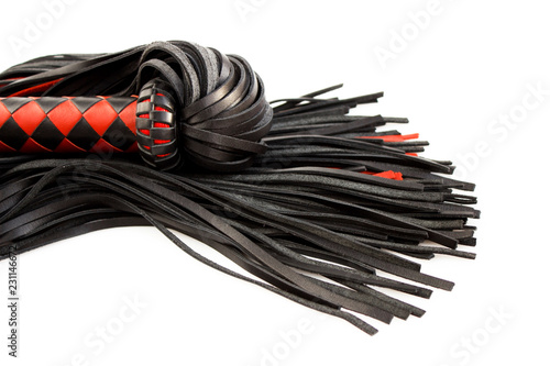 Red-black floger with a patterned handle and leather tails on white background.concept of pleasure from pain