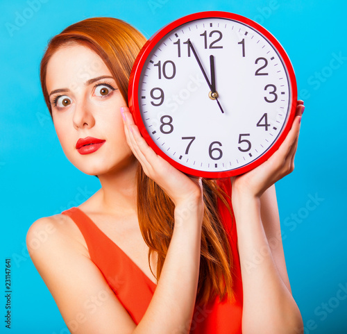 Redhead girl with huge clock on blue background.
