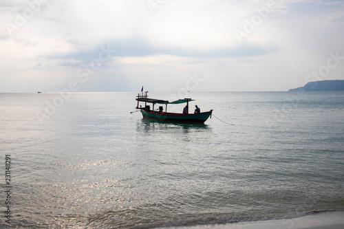 Traditional wooden boat in Cambodia. Sunrise sea landscape photo. Sea and sky view with boat silhouette.