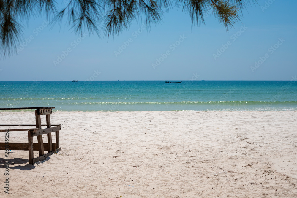 White sand beach with rustic wooden bench and table. Tropical island in South Asia. Turquoise blue sea landscape.