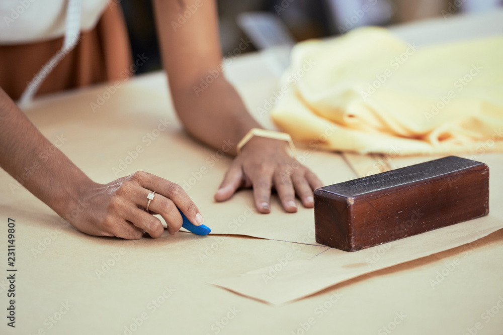 Close-up of female tailor drawing with soap markup patterns on fabric at the table Close-up of female tailor drawing with soap markup patterns on fabric at the table