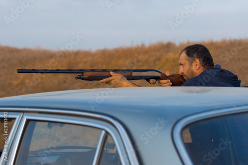 The guy shoots cartridges with a gun in nature, The hunter shoots at the target at sunset