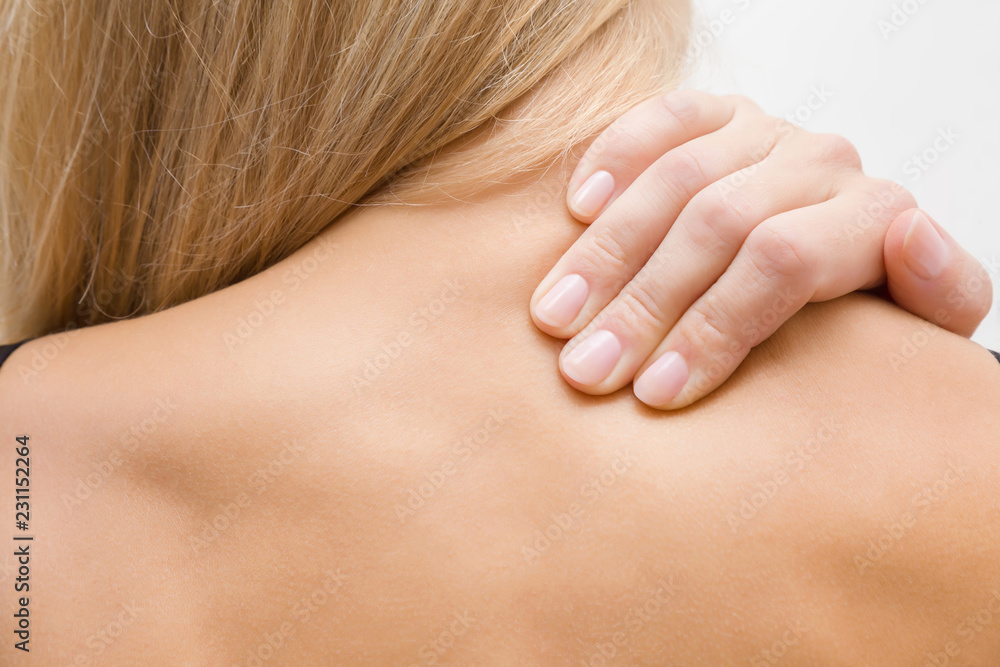 Young, blonde woman massaging her naked shoulder with hand. Pain from strain and incorrect posture. Inactive lifestyle. Young, blonde woman massaging her naked shoulder with hand. Pain from strain and incorrect posture. Inactive lifestyle.