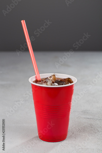 red Cup with soda and red straws on grey background