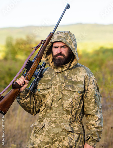 Hunting big game typically requires tag each animal harvested. Hunting season. Guy hunting nature environment. Bearded hunter rifle nature background. Experience and practice lends success hunting