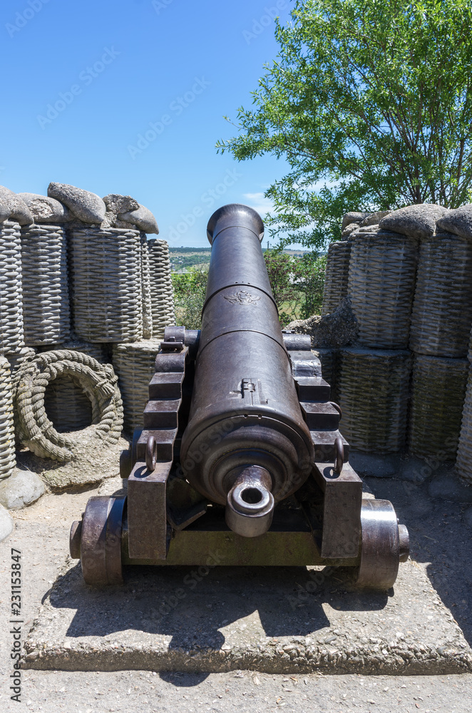 Old cast-iron cannon in a combat position. Reconstruction of the fortifications of the 4th bastion of the times of the Krymkoy War and the defense of Sevastopol Old cast-iron cannon in a combat position. Reconstruction of the fortifications of the 4th bastion of the times of the Krymkoy War and the defense of Sevastopol