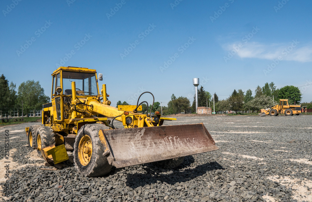 Yellow loader with empty bucket stands on a stone gravel during road construction works. The stones for the road. Unloading stone. Yellow loader with empty bucket stands on a stone gravel during road construction works. The stones for the road. Unloading stone.