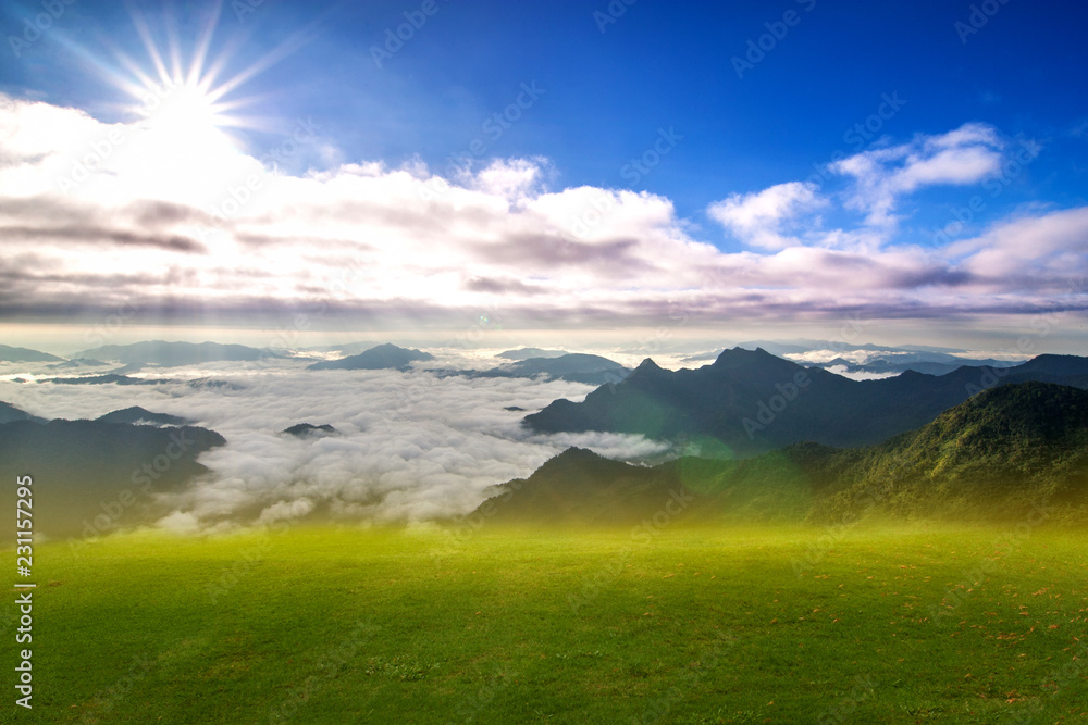Beautiful scenery of empty  Green meadow with misty covered the mountains as the background in sunrise, sunset time.