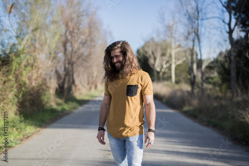 young man with long hair posing in the middle of a path
