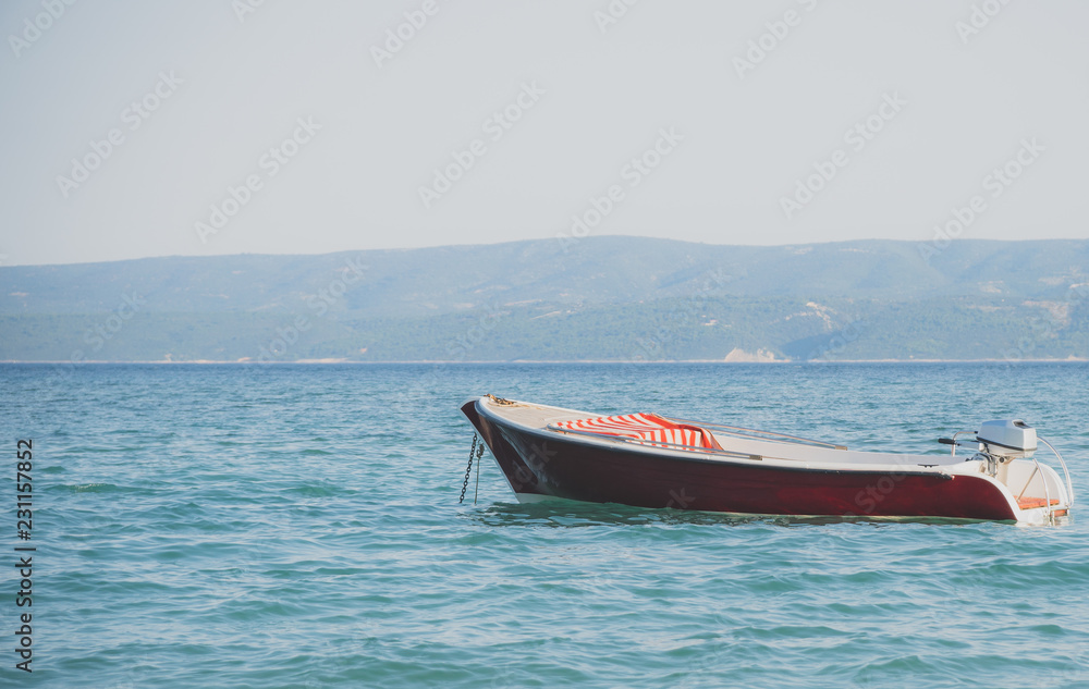 Fototapeta premium Lonely red boat moored in the open sea.