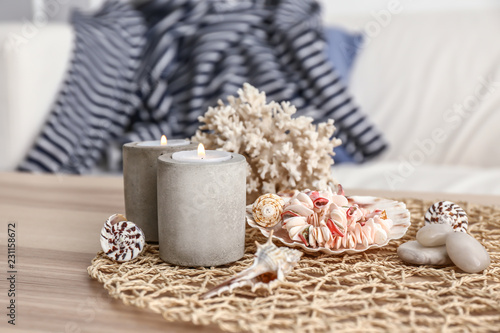 Burning candles and seashells on wooden table
