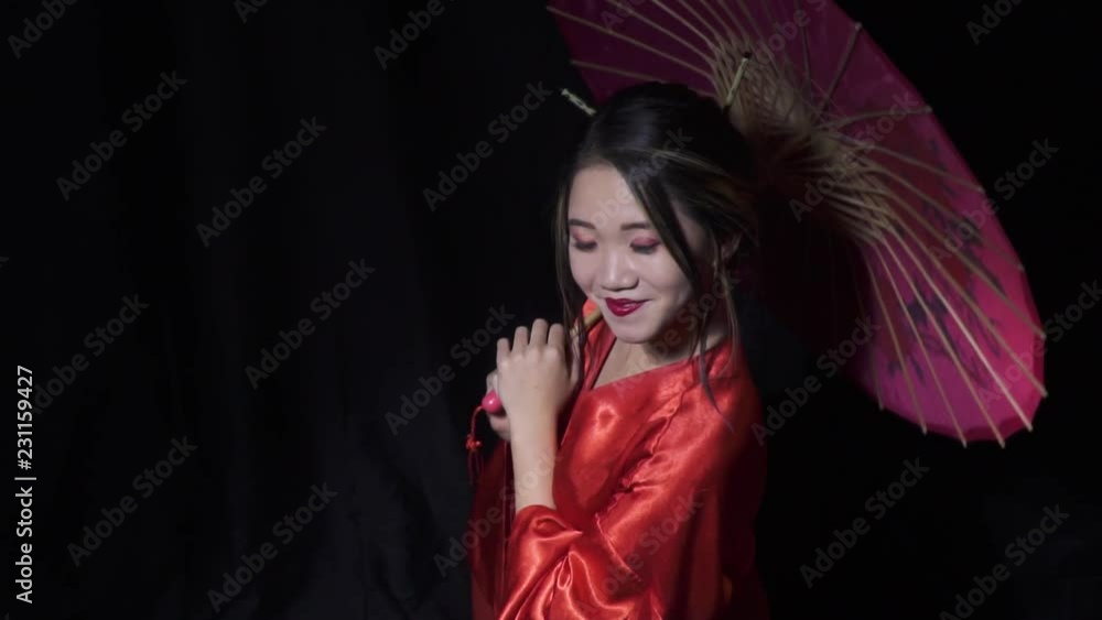 Beautiful japanese woman peeks from under the umbrella with a smile Beautiful japanese woman peeks from under the umbrella with a smile