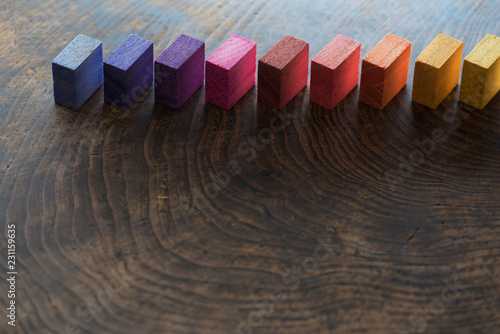 Colored wooden blocks diagonally aligned on a old vintage wooden table. For something with concept of variations or diversity. Plenty of copy space for cover or header image usage. photo