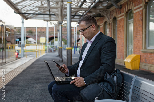 BUSINESS MAN USING HIS TABLET AND PHONE OUTSIDE OFFICE
