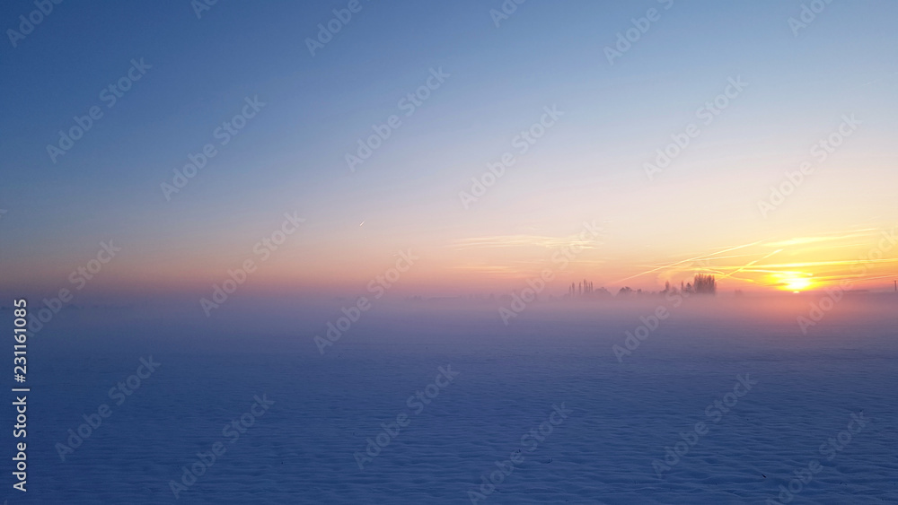 beautiful sunset in blue light  in a rural landscape covered with snow