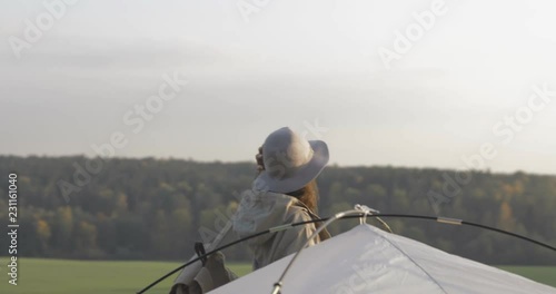 The girl sets up a tent on the grass. Tourist fortifies the tent, camping. Female caucasian model on vacation 4k video photo