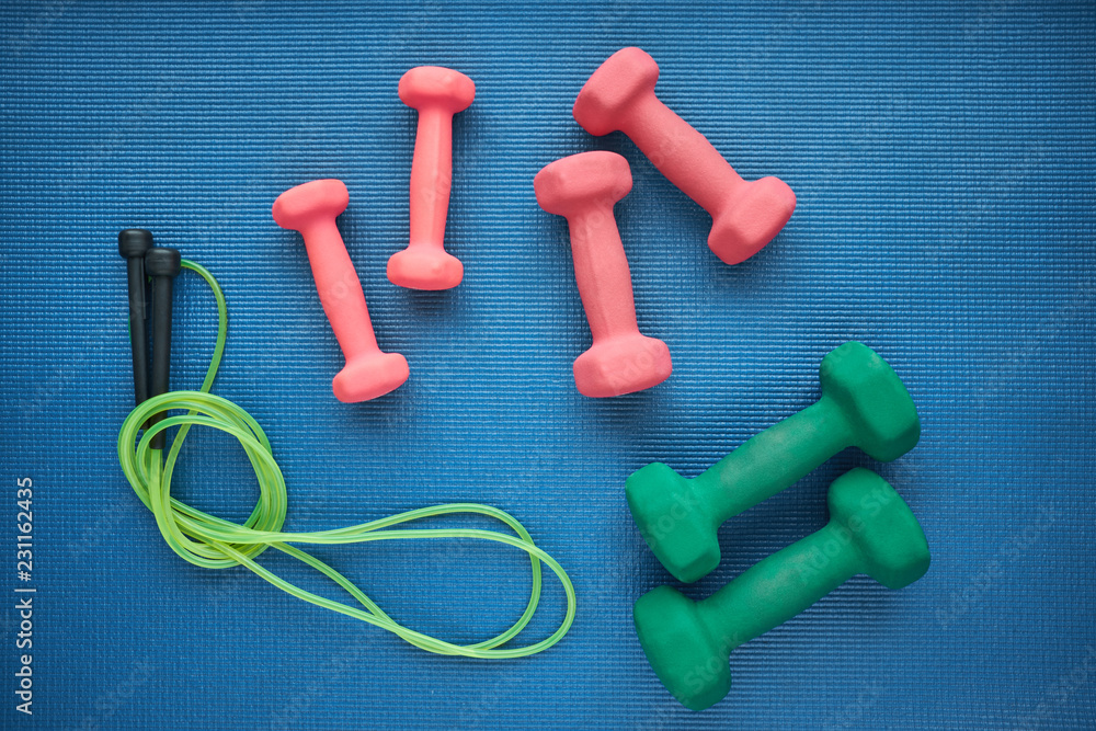 Set of jump rope and dumbeells on the blue background, top view Set of jump rope and dumbeells on the blue background, top view