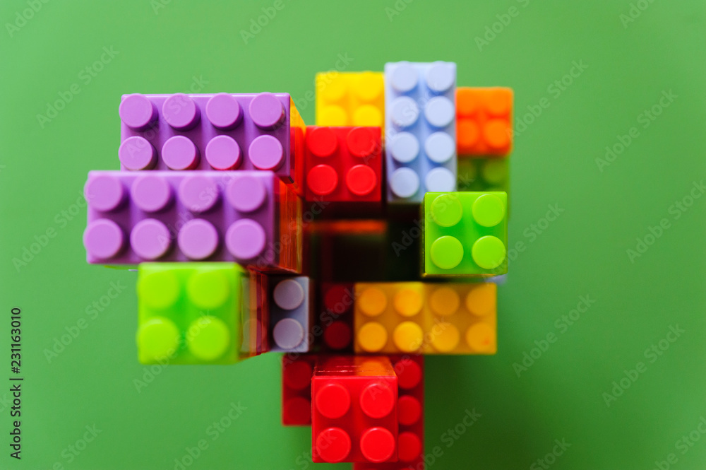 Top view of a children construction made out of colored blocks isolated on a green background. Top view of a children construction made out of colored blocks isolated on a green background.