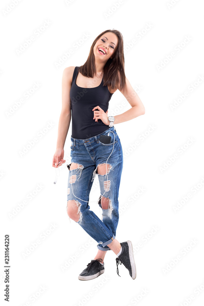 Carefree funky confident girl holding earphones laughing and looking away. Full body isolated on white background. Carefree funky confident girl holding earphones laughing and looking away. Full body isolated on white background.