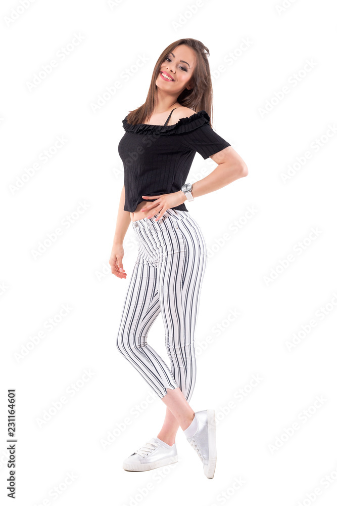 Side view of relaxed young woman fashion model in striped pants posing and smiling at camera. Full body isolated on white background. Side view of relaxed young woman fashion model in striped pants posing and smiling at camera. Full body isolated on white background.