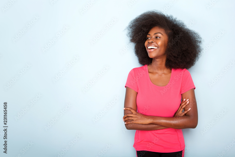 smiling young black woman with arms crossed against blue background smiling young black woman with arms crossed against blue background