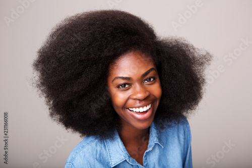 Close up happy young african american woman laughing against isolated gray background