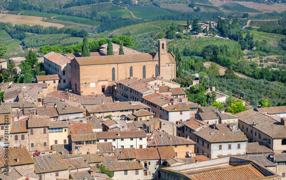 Rooftop view on Tuscany town and fields. San Gimignano medieval city houses and natural landscape, Italy