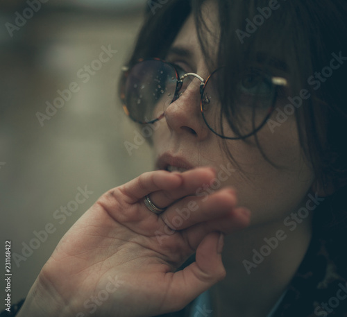 Portrait of pensive woman with misted glasses in dusk.