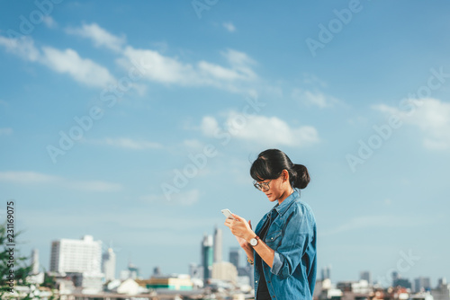 Asian woman used smart phone reads and text message on her smart phone in the city scene background with copy space