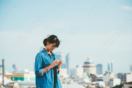 Asian woman used smart phone reads and text message on her smart phone in the city scene background with copy space