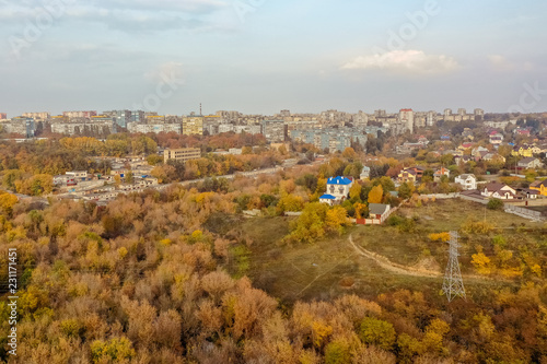 Aerial top view of colorful autumn forest in front of the city. Background of trees in yellow and green color.