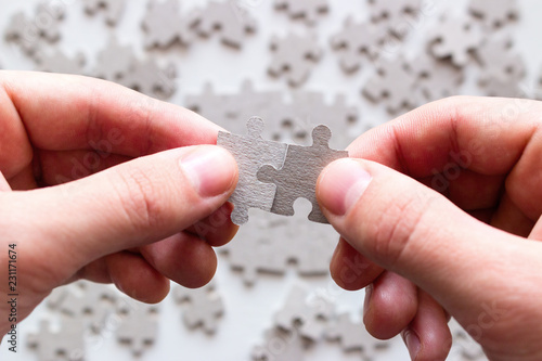 businessman hands trying to collect pieces of the puzzle on a background of other details