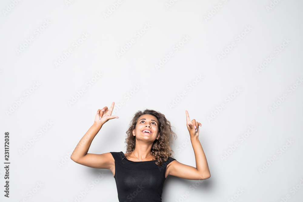Portrait of happy curly woman pointing up and smiling against white background Portrait of happy curly woman pointing up and smiling against white background