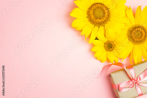 Fototapeta Naklejka Na Ścianę i Meble -  Pink background with yellow sunflowers and gift box.