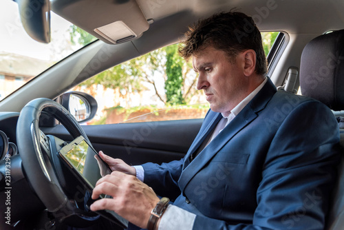 Businessman working on tablet inside car on bright day © Jevanto Productions