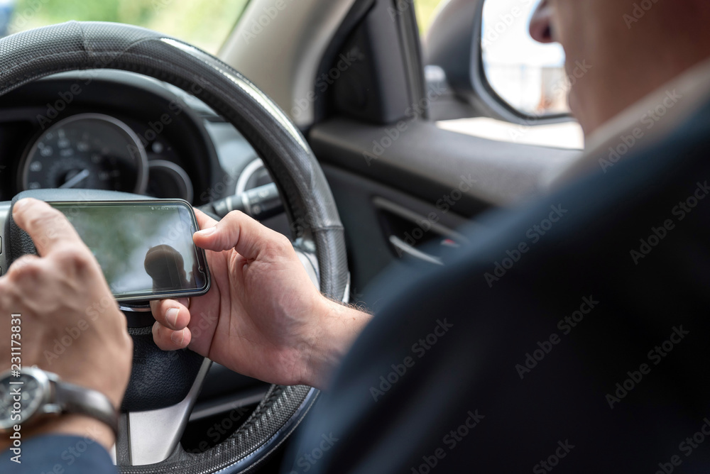 Businessman working on tablet and smartphone inside car on bright day