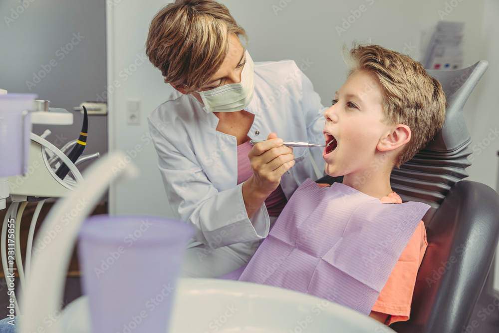 Dentist examining boy's teeth with dental instruments Dentist examining boy's teeth with dental instruments