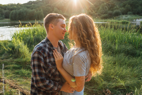 Romantic couple spending time in nature, kissing at sunset photo