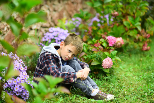 Unhappy and miserable. Little boy in deep sorrow. Little boy with sad look hide in garden. Little children little sorrow © Volodymyr