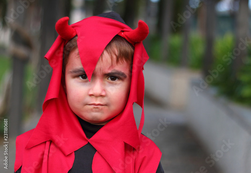 niño disfrazado de demonio con cuernos con cara de malo photo