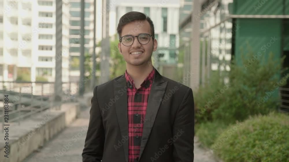 Static shot of positive Indian young man smiling at camera. South Asian manager wearing glasses and smart suit posing for company advertisement. Successful candidate concept Static shot of positive Indian young man smiling at camera. South Asian manager wearing glasses and smart suit posing for company advertisement. Successful candidate concept