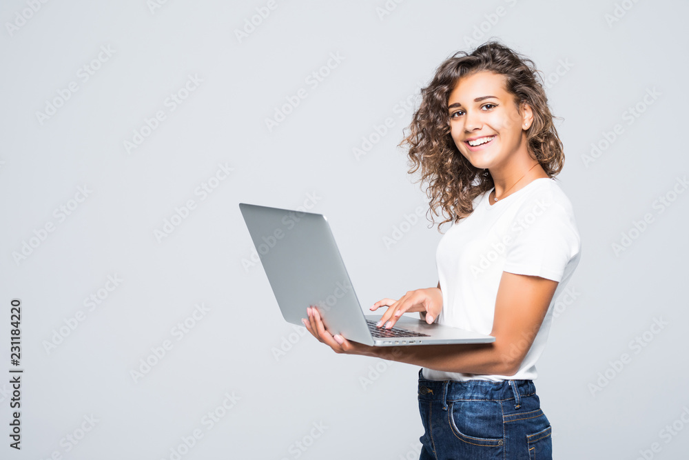 Young mixed race cool woman with curly hair using laptop and smiling isolated over white background Young mixed race cool woman with curly hair using laptop and smiling isolated over white background