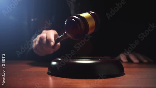 Judge hitting Gavel off a block in courtroom, dark background slow motion dolly shot photo