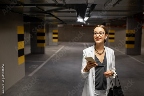 Portrait of a young business woman with smart phone in the underground car parking of the new residential building