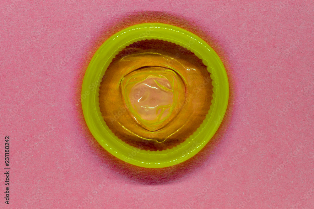 Yellow color condom on pink background surface Yellow color condom on pink background surface