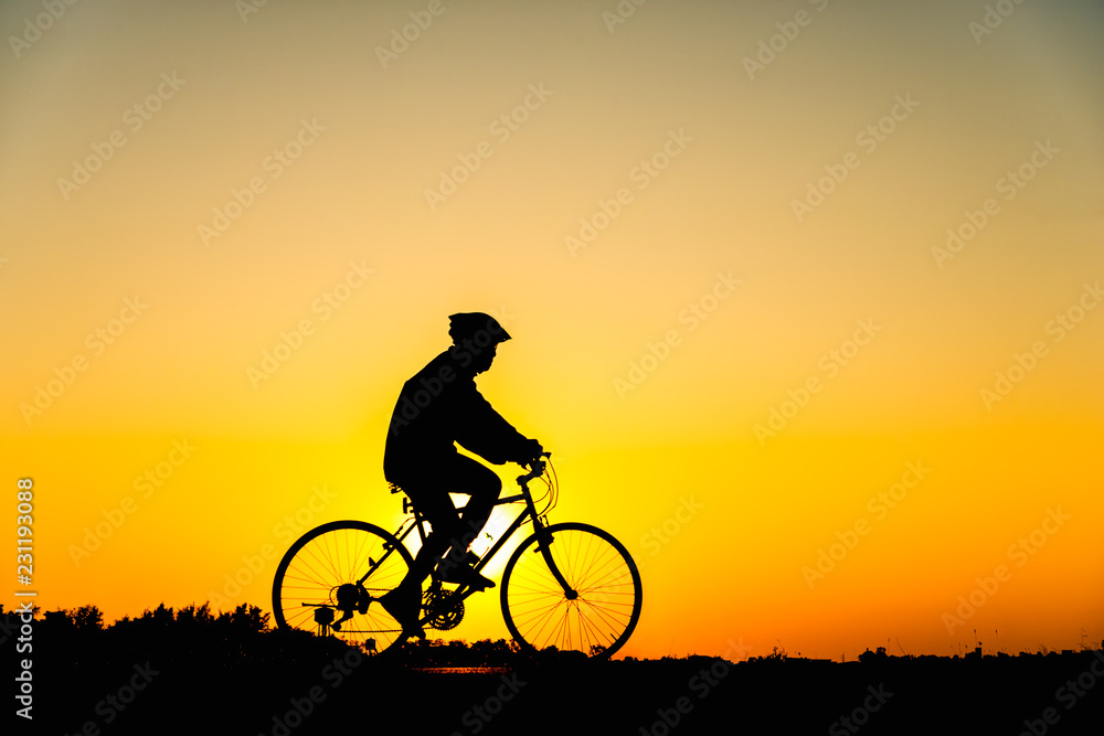 Fototapeta premium Silhouette man cycling on sunset background
