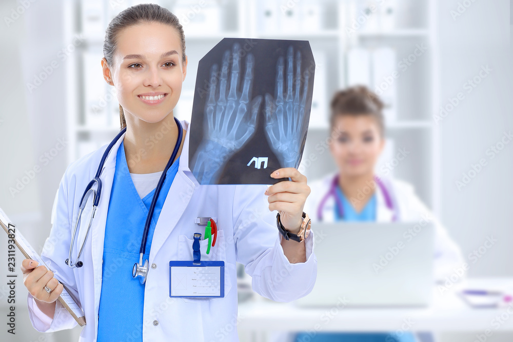 Beautiful young smiling female doctor sitting at the desk and writing. Beautiful young smiling female doctor sitting at the desk and writing.
