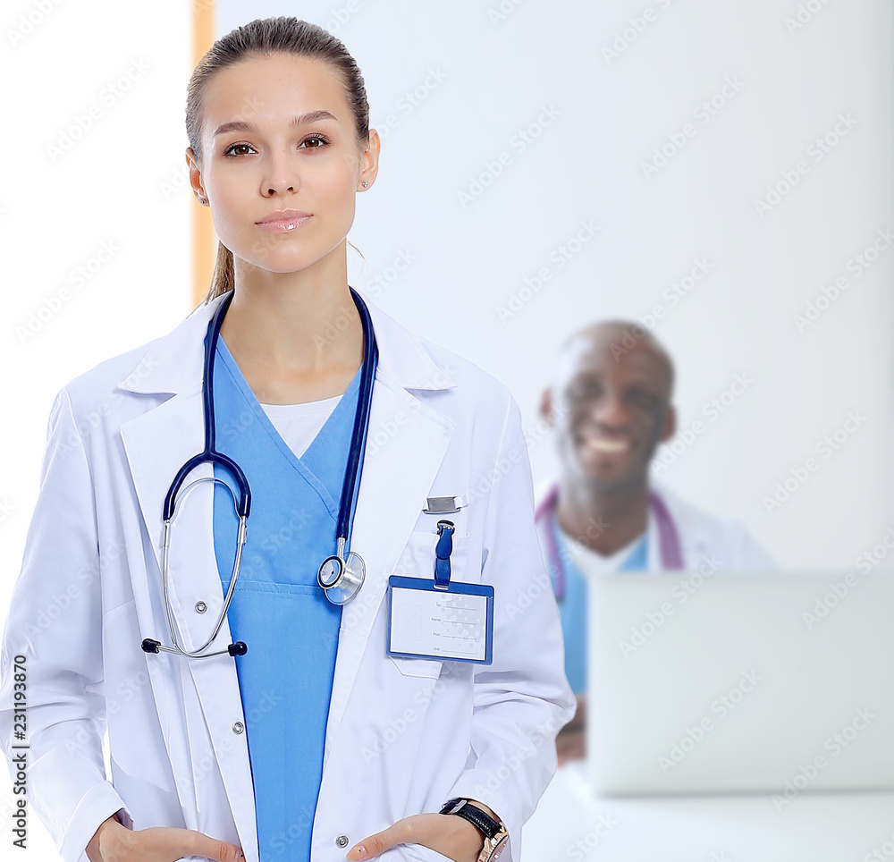 Beautiful young smiling female doctor sitting at the desk and writing. Beautiful young smiling female doctor sitting at the desk and writing.