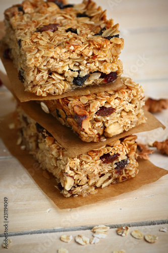 Homemade granola bars with nuts and cranberries over wooden background
