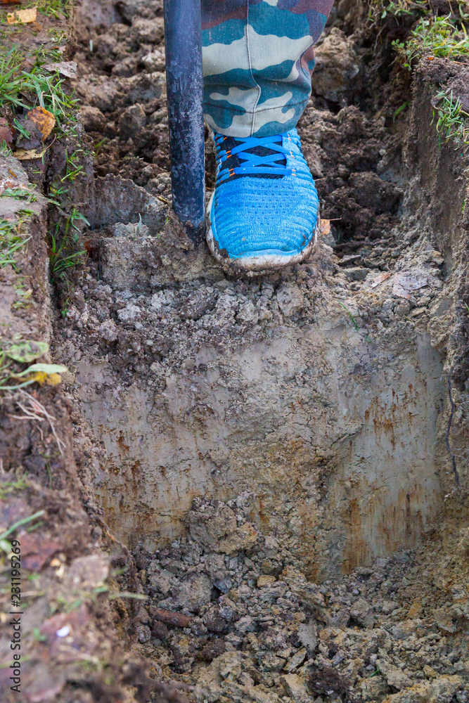 Obraz premium Man digging a ditch with a shovel in autumn